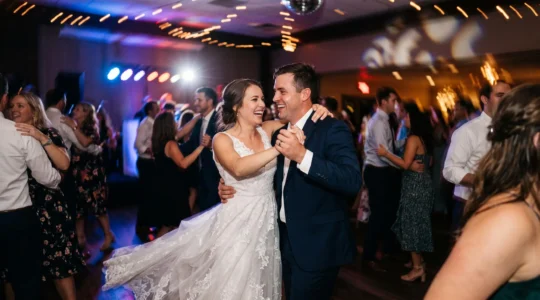 Wide editorial photograph of a wedding couple dancing amid blurred light trails on a dance floor at night
