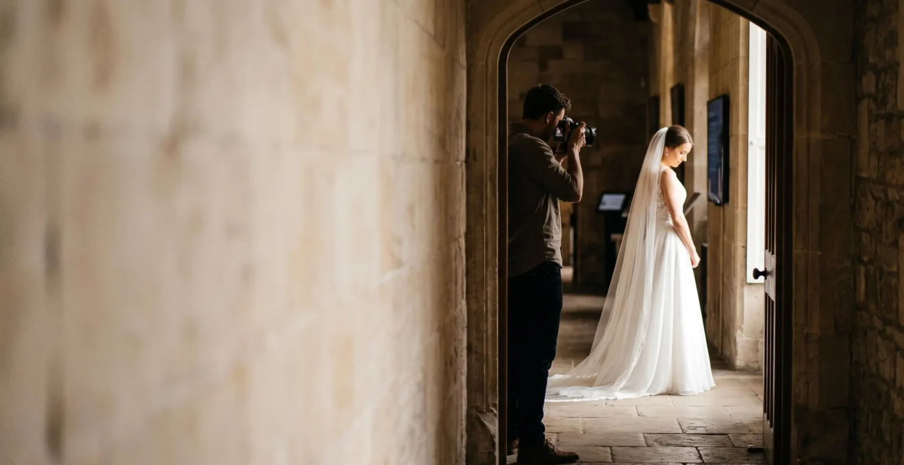A wedding photographer studying the natural light falling through a large window onto a bride, without using any flash equipment.