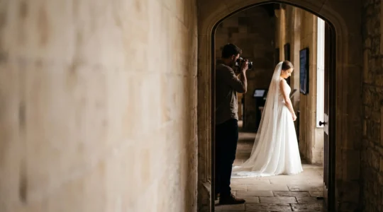 A wedding photographer studying the natural light falling through a large window onto a bride, without using any flash equipment.